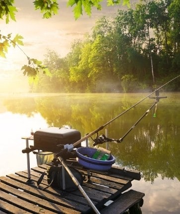 A fishing rod on a dock in a lake.