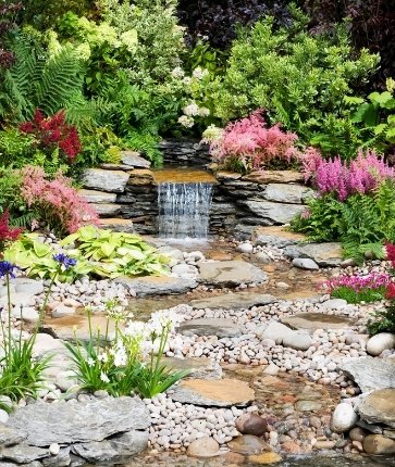 A garden with a water feature and colorful flowers.