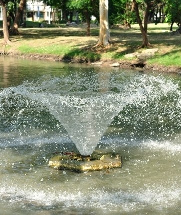 A fountain with water spraying out of it in a park.