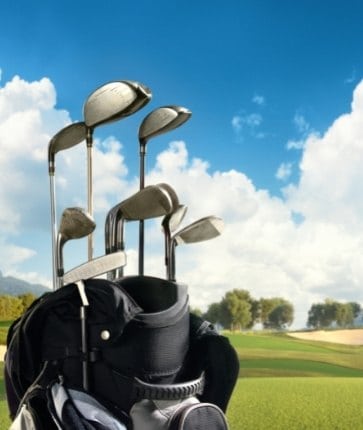 Golf clubs in a bag on a green field.