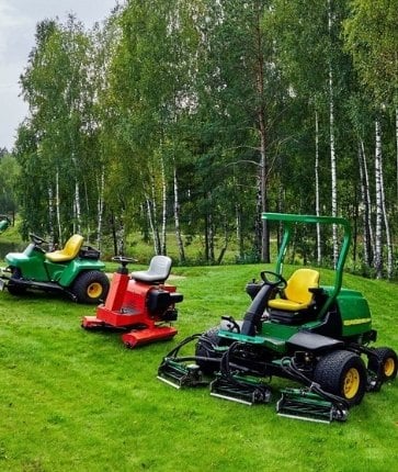 A group of lawn mowers parked on a grassy field.