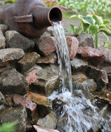 A water fountain in a garden with rocks.