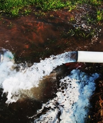 A pipe is being drained of water in a field.