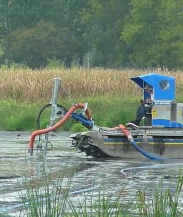 A man is driving a boat through a flooded field.
