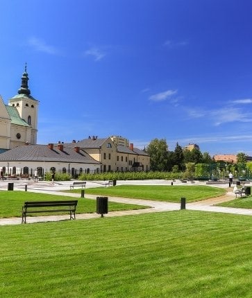 A park with benches and a church in the background.
