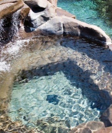 A pool with a waterfall in the middle of it.