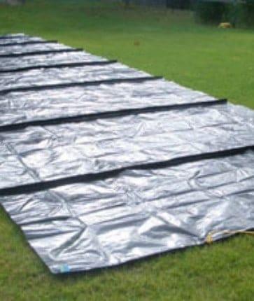A large tarp is laid out on a grassy field.