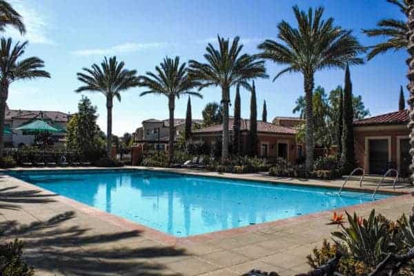 An apartment complex with a swimming pool and palm trees.