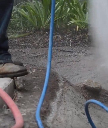 A person is spraying concrete with a hose.