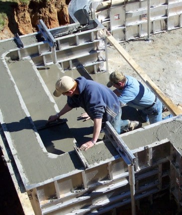 Two men working on a concrete slab.