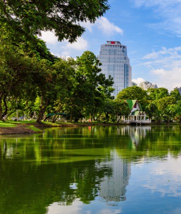 A lake surrounded by green trees and buildings in bangkok, thailand.