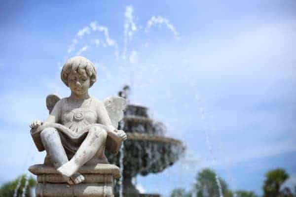 A statue of a boy sitting in front of a fountain.