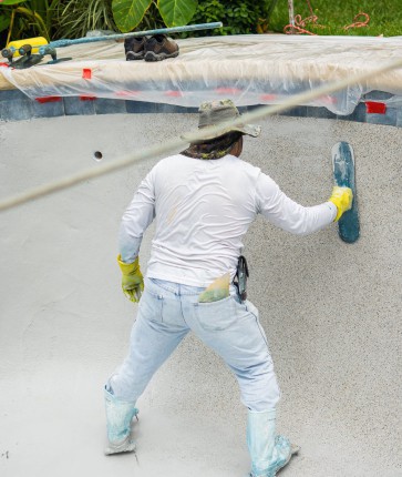 A man is working on a concrete pool.